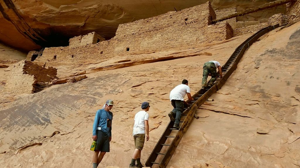young men climbing up rock face